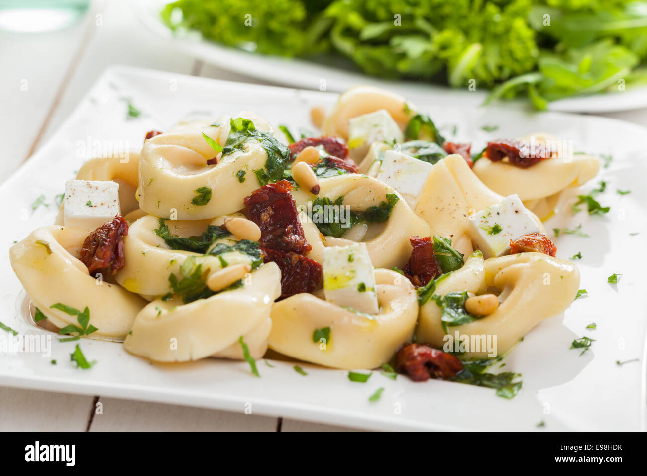 Gefüllte italienische Tortellini Nudeln Nudeln mit Feta-Käse, frischem Basilikum und Pinienkernen serviert mit einem grünen Salat Stockfoto