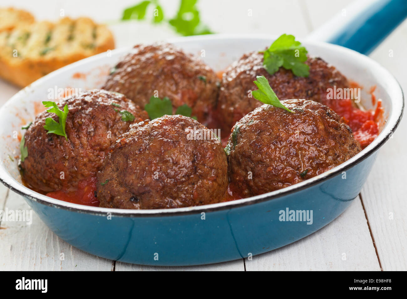 Pfanne mit fünf herzhafte italienische Hackfleischbällchen in würziger Tomatensauce mit frischem Basilikum, niedrigen Winkel Detailansicht garniert Stockfoto