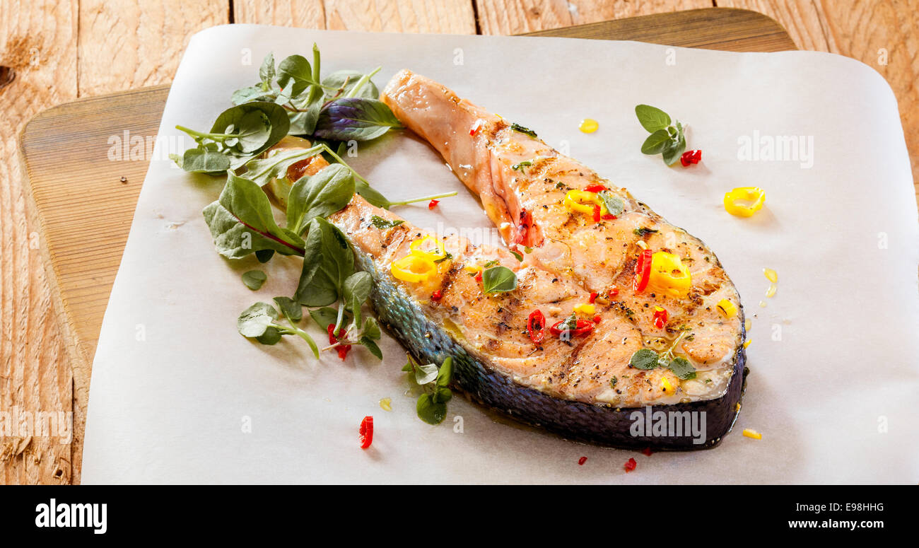 Gegrilltes Lachsfilet mit Gewürzen, Zwiebeln und Kräutern gewürzt serviert auf einem Holzbrett in ein Fischrestaurant für ein Gourmet-Menü Stockfoto