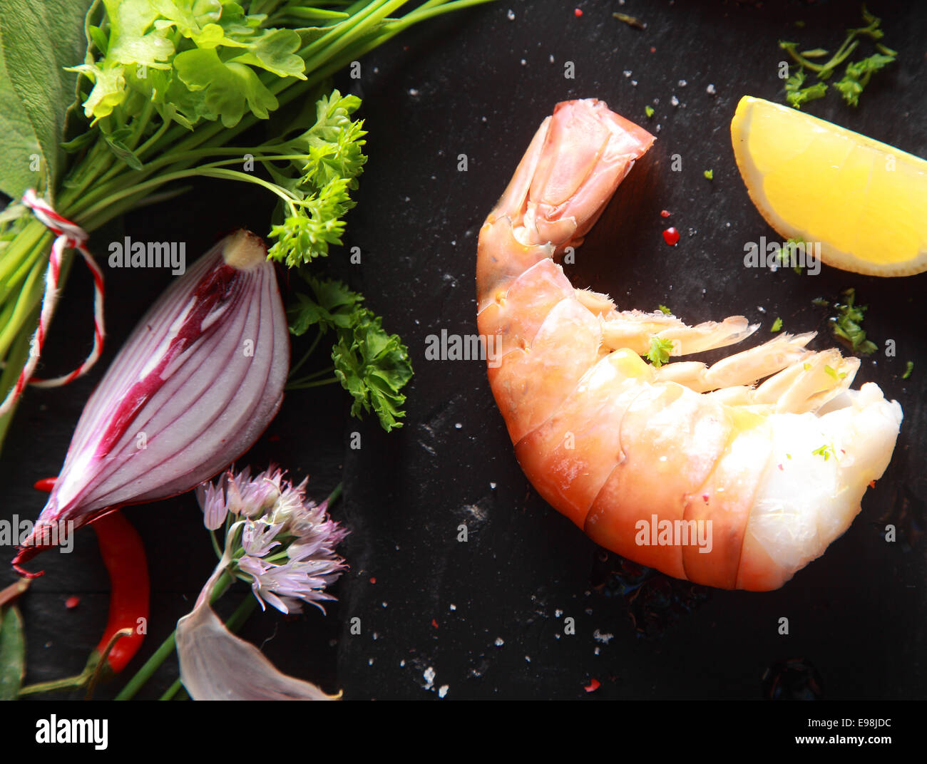 Einzelne Garnelen Fleisch mit Geschnetzeltes Zitrone und Zwiebeln auf schwarzen Holztisch Stockfoto