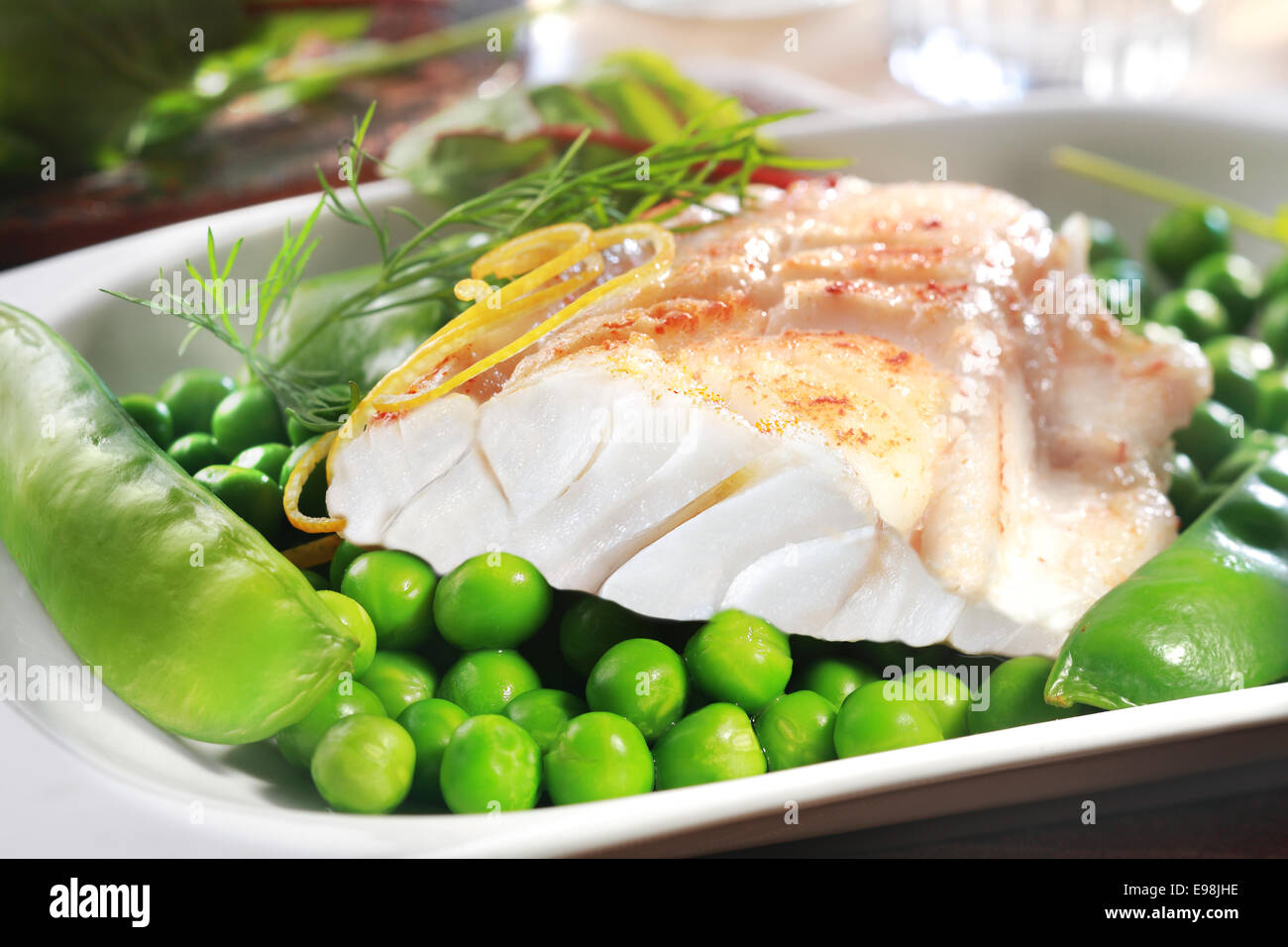 Gesunder Fisch vom Grill Steak mit Erbsen, Kefengemüse und Zitronenschale auf dem Silbertablett serviert als Vorspeise oder Hauptgericht Stockfoto