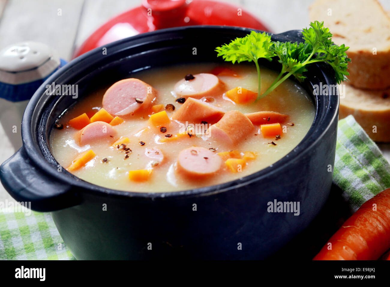 Mund Bewässerung cremige Suppe Hauptgericht mit Wurst auf Tuch am Holztisch hautnah. Stockfoto