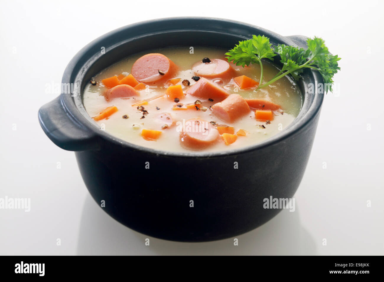 Appetitlich Hauptgericht Suppe Gericht Rezept auf schwarzen Topf auf grauem Hintergrund isoliert. Stockfoto