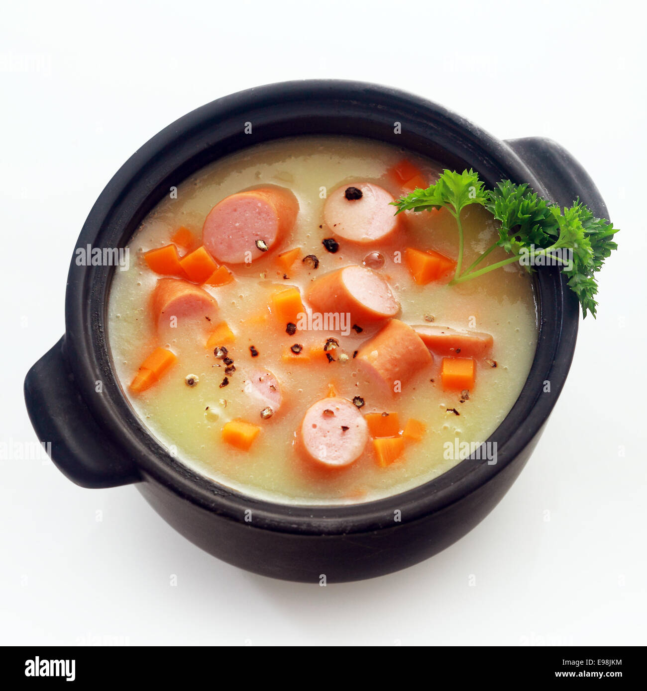 Schließen Sie sich gesunde Kurs appetitlich cremige Suppe Hauptgericht mit Wurstscheiben auf schwarzen Topf, Isolated on White Background. Stockfoto