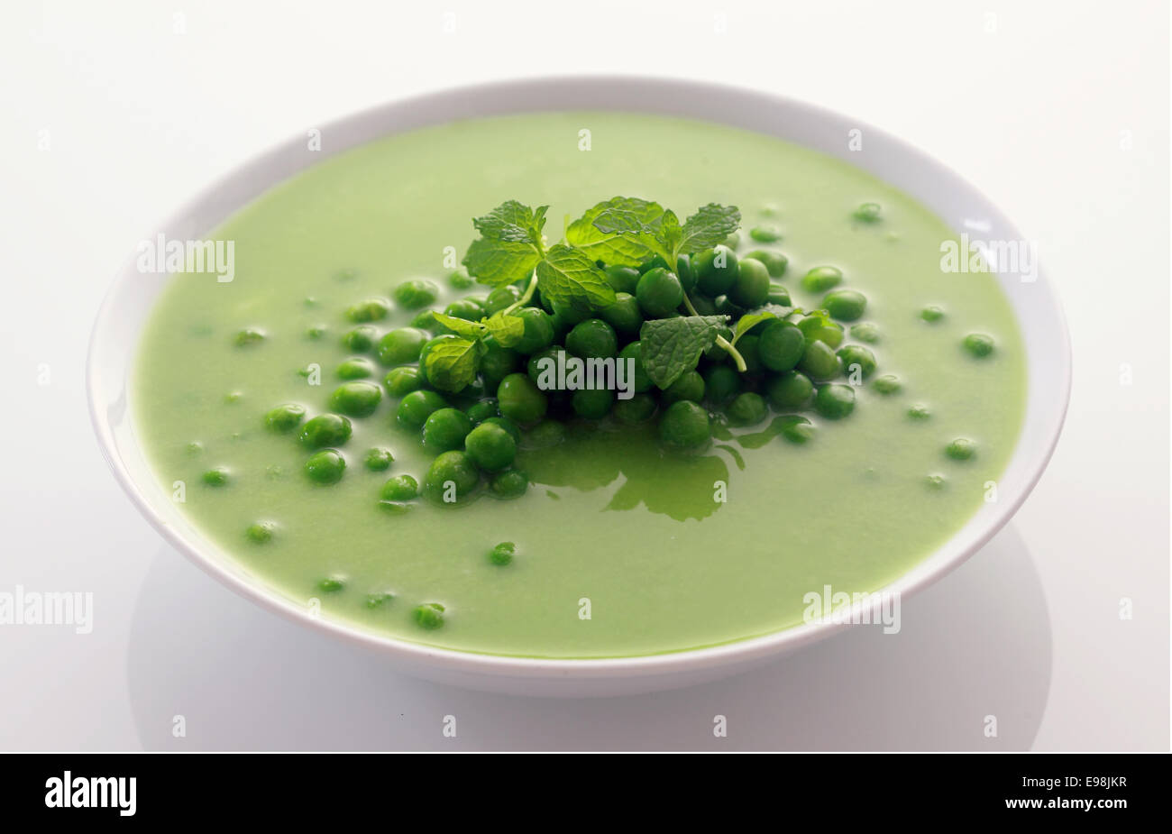 Schließen Sie appetitlich gesunde grüne Erbsen Suppe auf weiße Schüssel isoliert auf weißem Hintergrund. Stockfoto