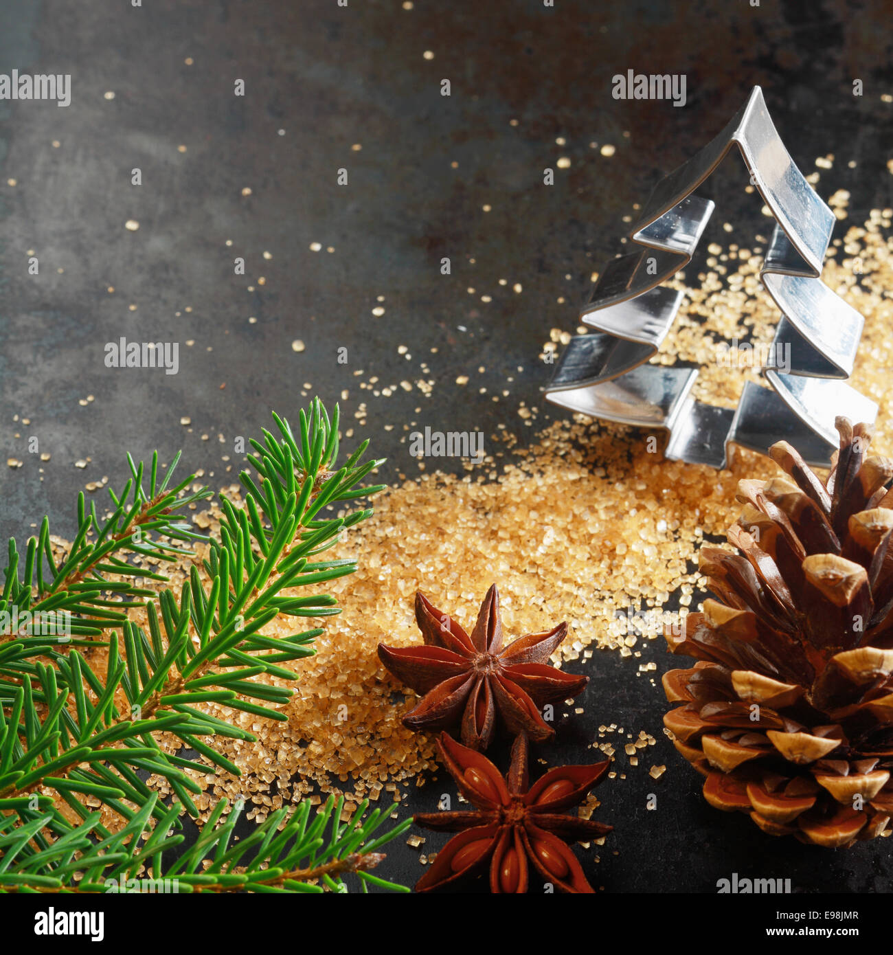 Weihnachts-Grußkarte-Hintergrund mit einem Ausstecher in Form eines Weihnachtsbaumes mit Tannenzweig, Kegel, karamellisierten braunen Zucker und Sternanis würzen auf einem dunklen Hintergrund mit Exemplar Stockfoto
