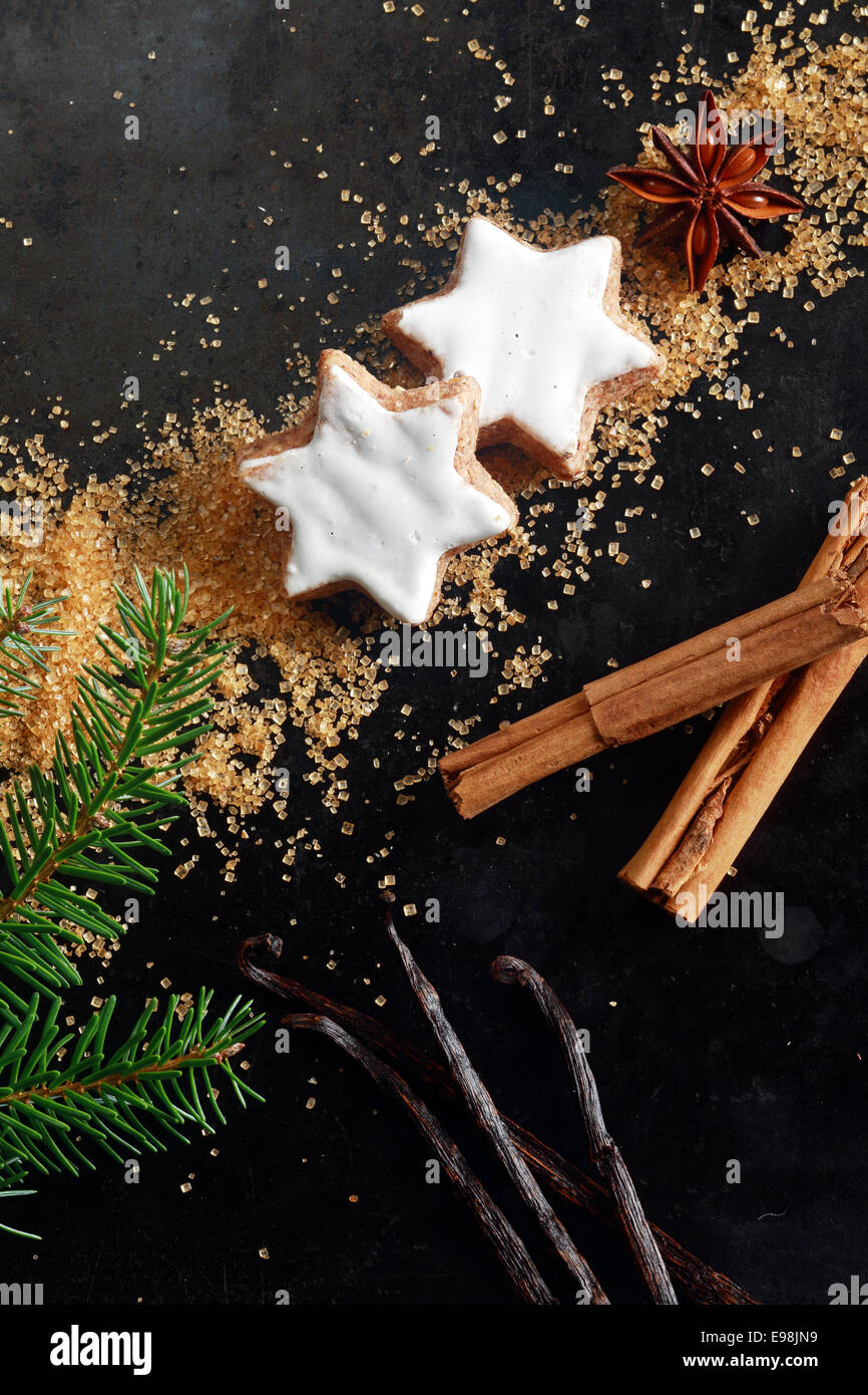 Weihnachten Essen Stilleben mit Exemplar für Ihre saisonalen Gruß mit eine Draufsicht des verglasten weißen Stern geformt, Cookies, Vanilleschoten, Zimtstange und Zucker auf einem dunklen Hintergrund Stockfoto
