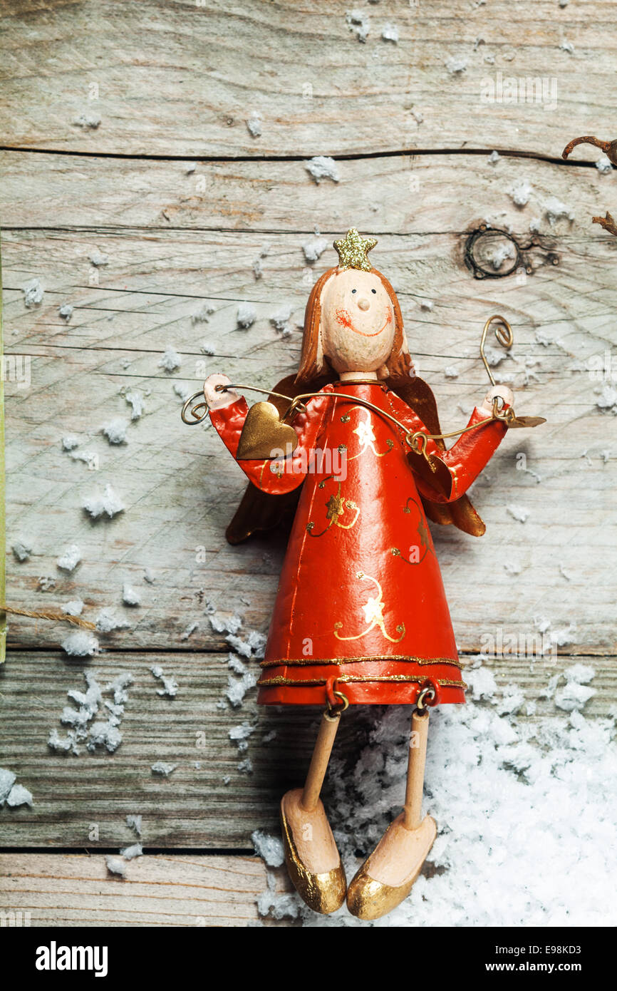 Vintage Holz Weihnachtsengel in einem bunten roten Kleid im Landhausstil-Handwerk auf einem alten hölzernen Hintergrund mit Exemplar Stockfoto
