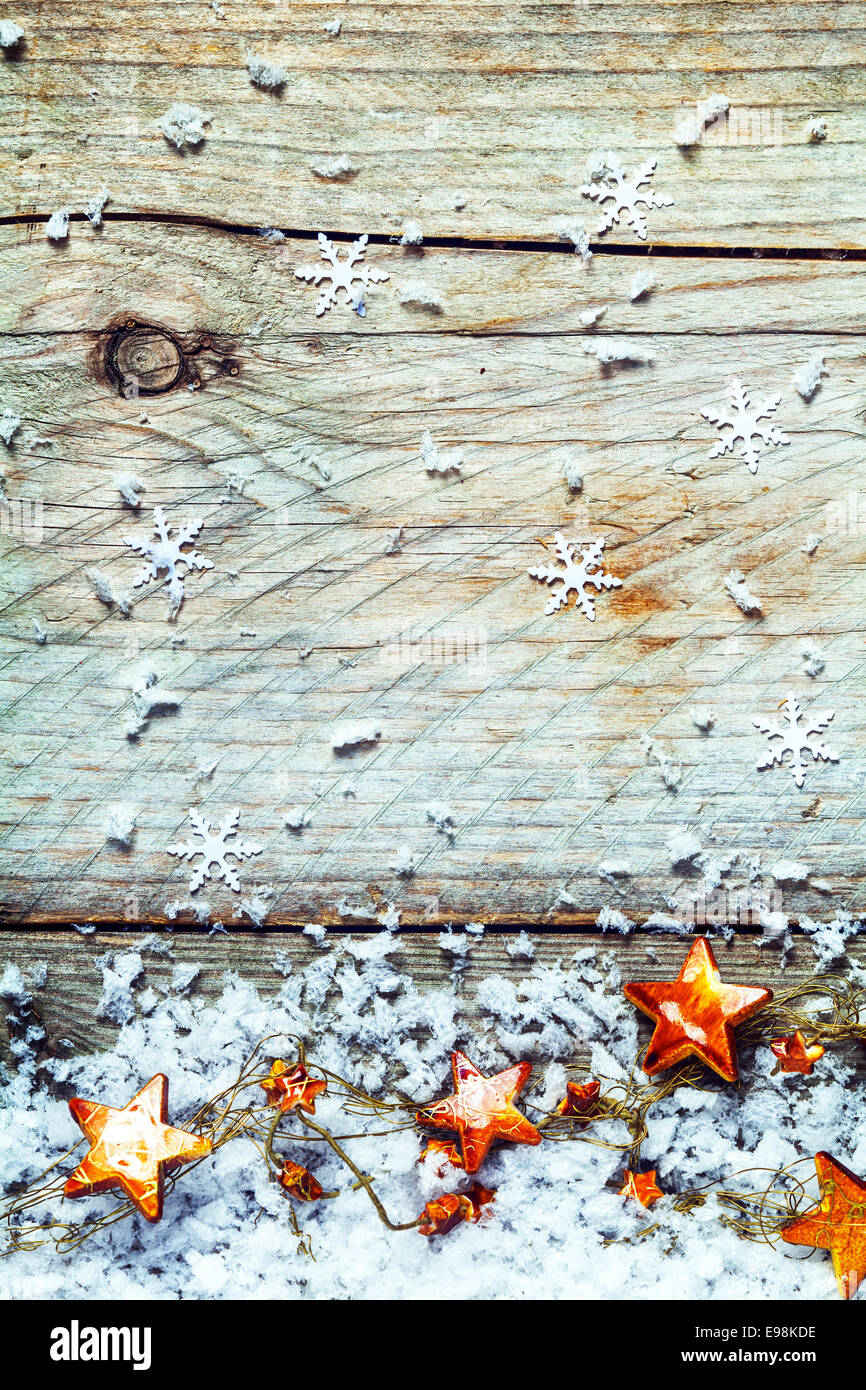 Garland Weihnachtssterne mit Schneeflocken in einem rustikalen Xmas-Hintergrund auf strukturierte Altholz mit Risse, Knoten und Exemplar Stockfoto