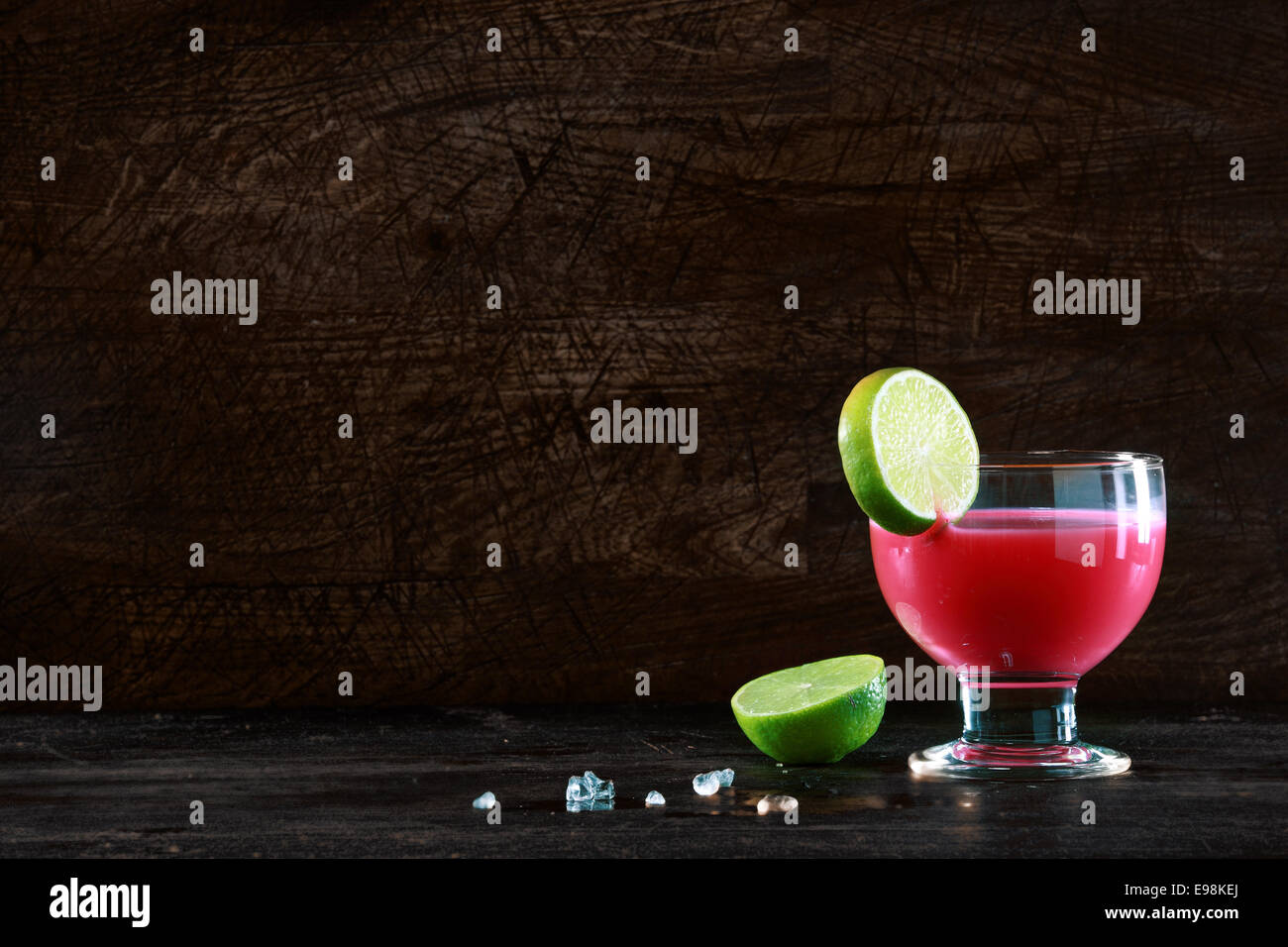Gesunde Frucht-Cocktail gemacht mit gemischten Beeren gemischt mit Alkohol, garniert mit einer Scheibe frischer Limette auf einer Bar steht vor einem dunklen Hintergrund mit Exemplar Zähler Stockfoto