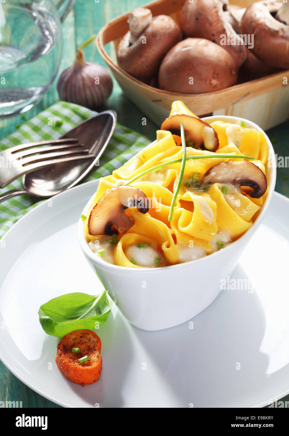 Bootsform Gericht der Pilz Tagliatelle mit eine Schale mit frischen Champignons im Hintergrund. Stockfoto