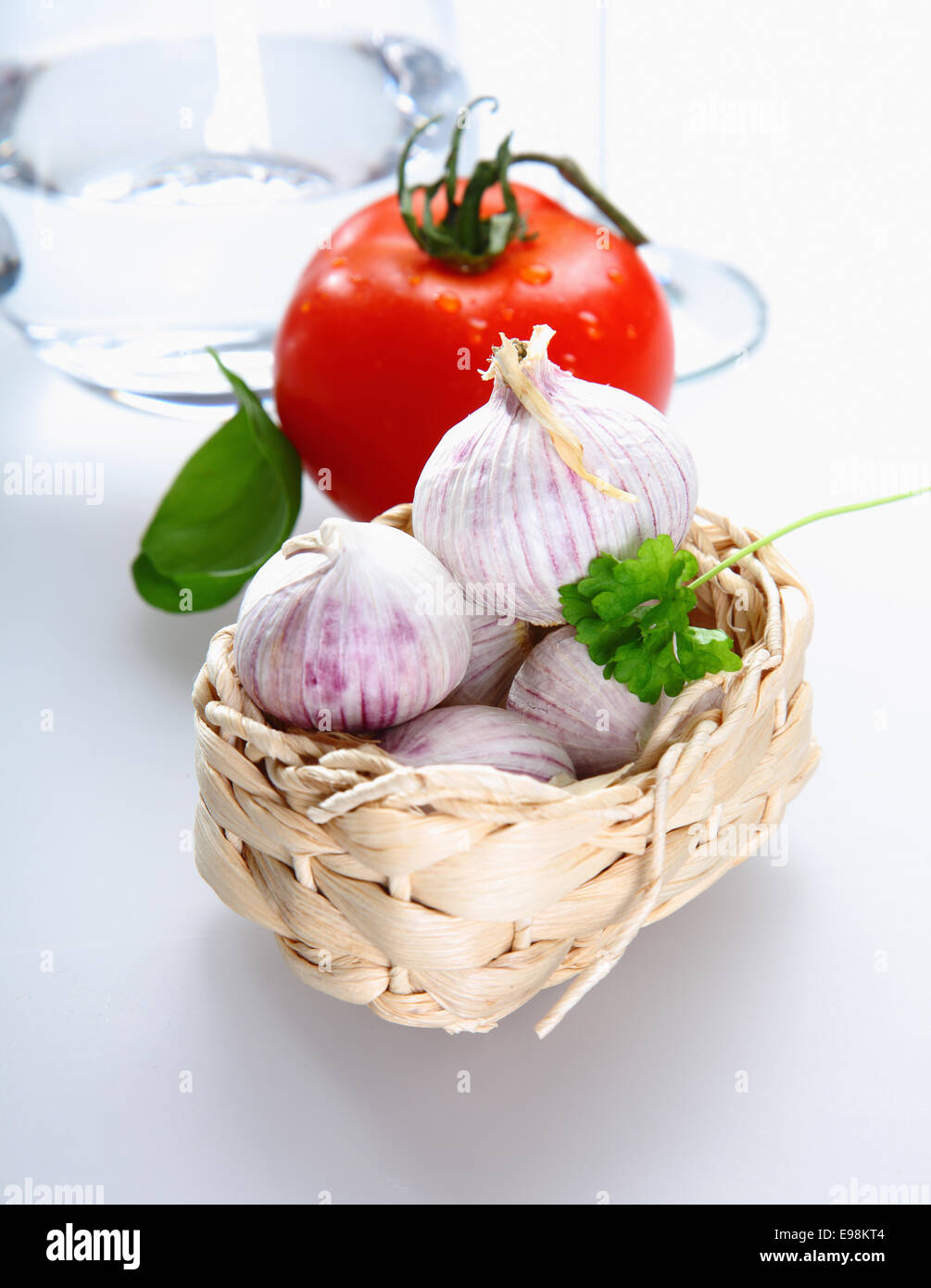 Ein Korb mit Tomaten, Knoblauch und Petersilie auf weißem Hintergrund für italienische Begriffe Stockfoto