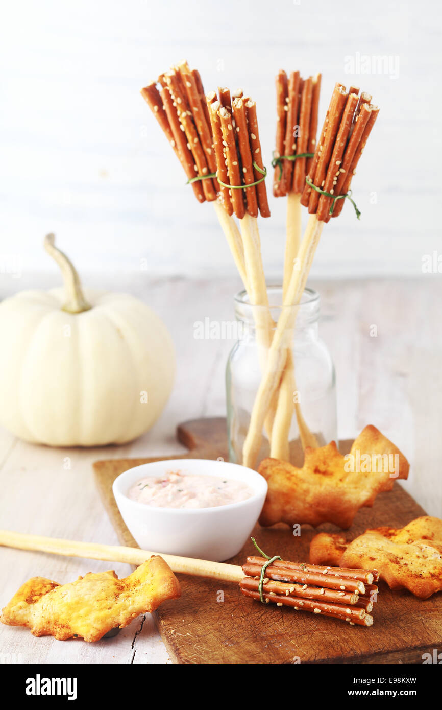 Rustikale Häppchen für eine Halloween-Party mit Hexen Besen hergestellt aus Brot-Sticks und Brezeln und Fledermaus-Kekse oder Kekse serviert mit einem herzhaften Sprung mit einem weißen Herbst Kürbis hinter Stockfoto