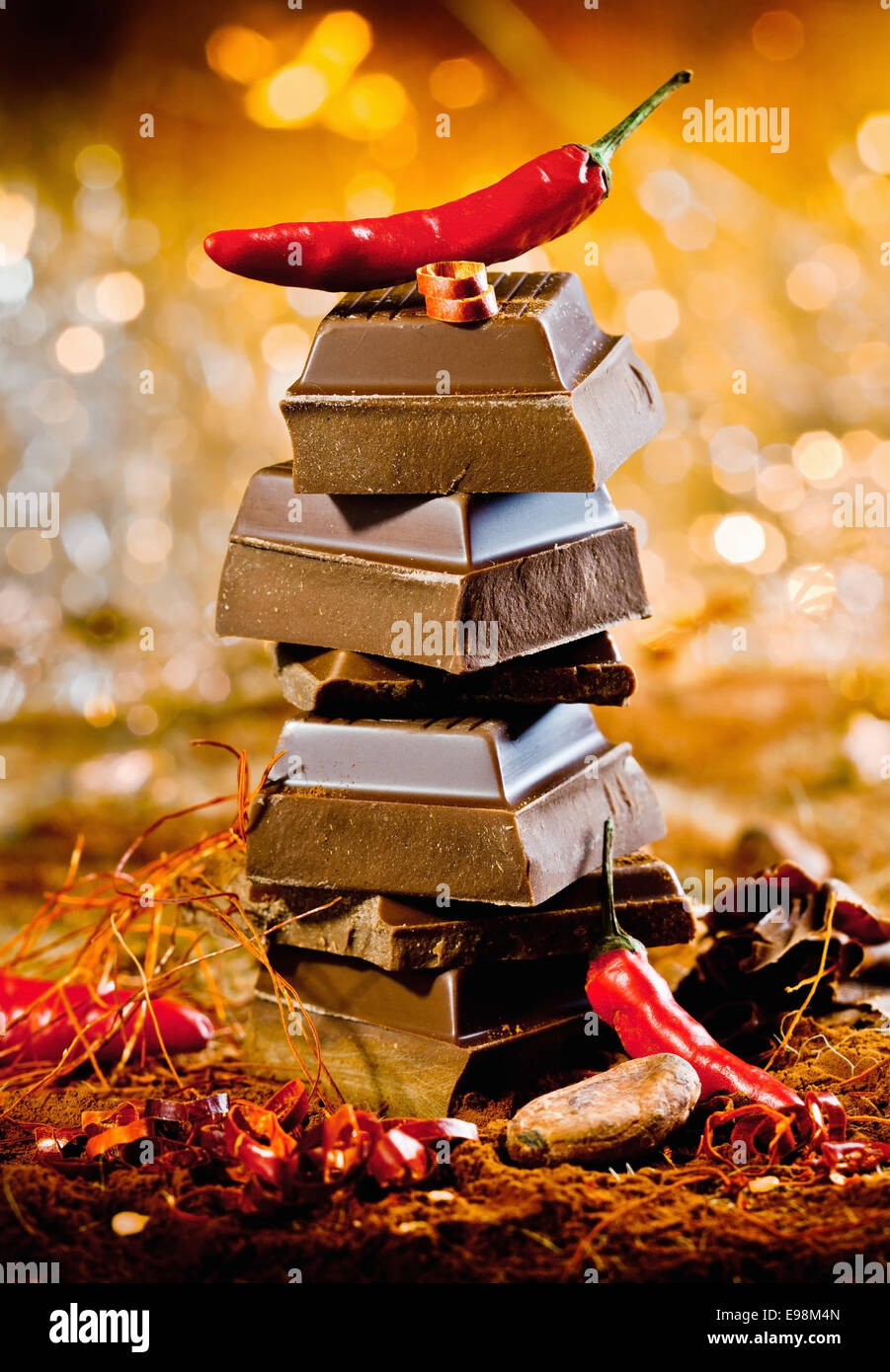 Konzeptbild für rote heiße Schokolade mit einem Turm von Schokolade Würfeln, gekrönt von einer feurigen Chili gegen ein Bokeh von festlichen Lichtern Stockfoto