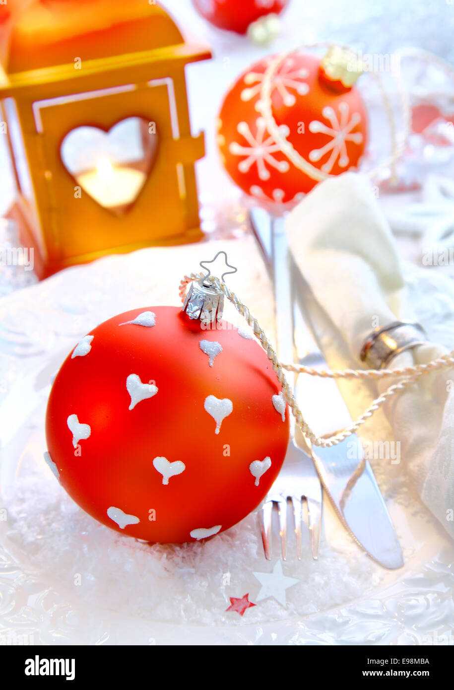 Rot Weihnachten Christbaumkugel auf verschneiten Hintergrund mit Gerichten und eine Serviette vor einer orange Laterne. Stockfoto