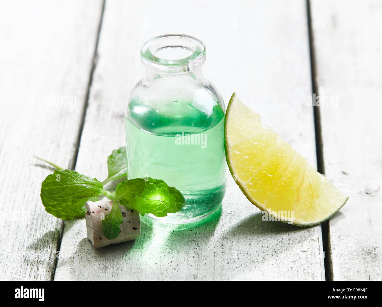 Kühle und erfrischende Minze ätherische Öl in eine klare Glasflasche mit Zitrone für einen erholsamen Spa-Behandlung Stockfoto