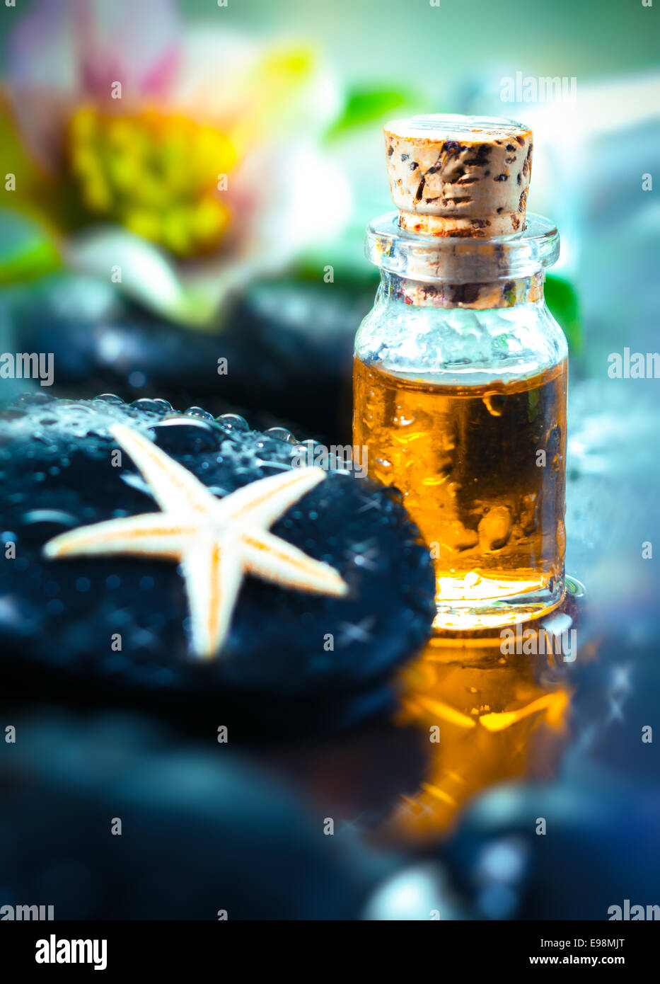 Goldene ätherisches Öl für eine Aromatherapie-Behandlung und Massage mit glatten schwarz und Massage Stein Stockfoto