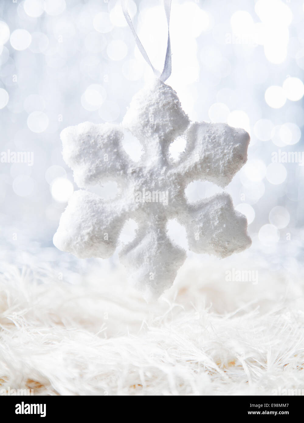 Leuchtende Schneeflocke auf defokussierten weißen Hintergrund mit bokeh Stockfoto
