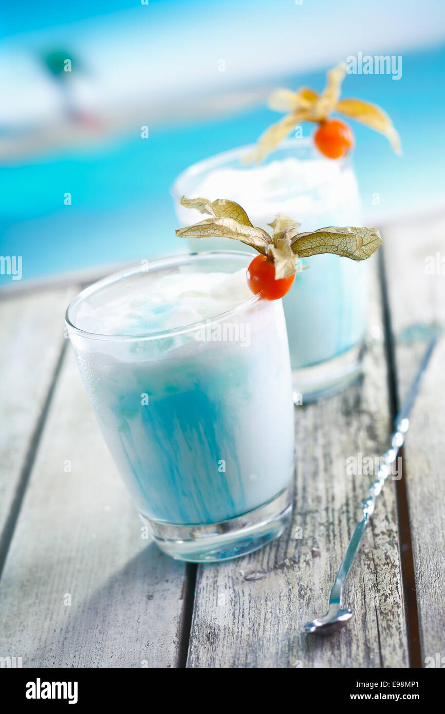 Zwei Gläser von gemischten blau kalt Curacao cocktail auf einer Terrasse mit Blick aufs Meer in einem tropischen resort Stockfoto