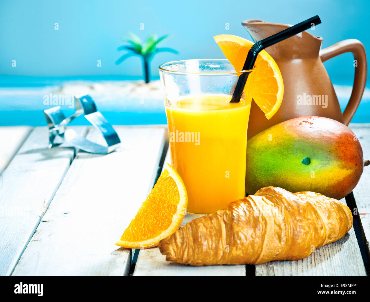 Tropisches Frühstück Stillleben mit einem gesunden Mango und orange Smoothie und eine frische reife Mango mit einem goldenen Croissant gegen eine Stockfoto