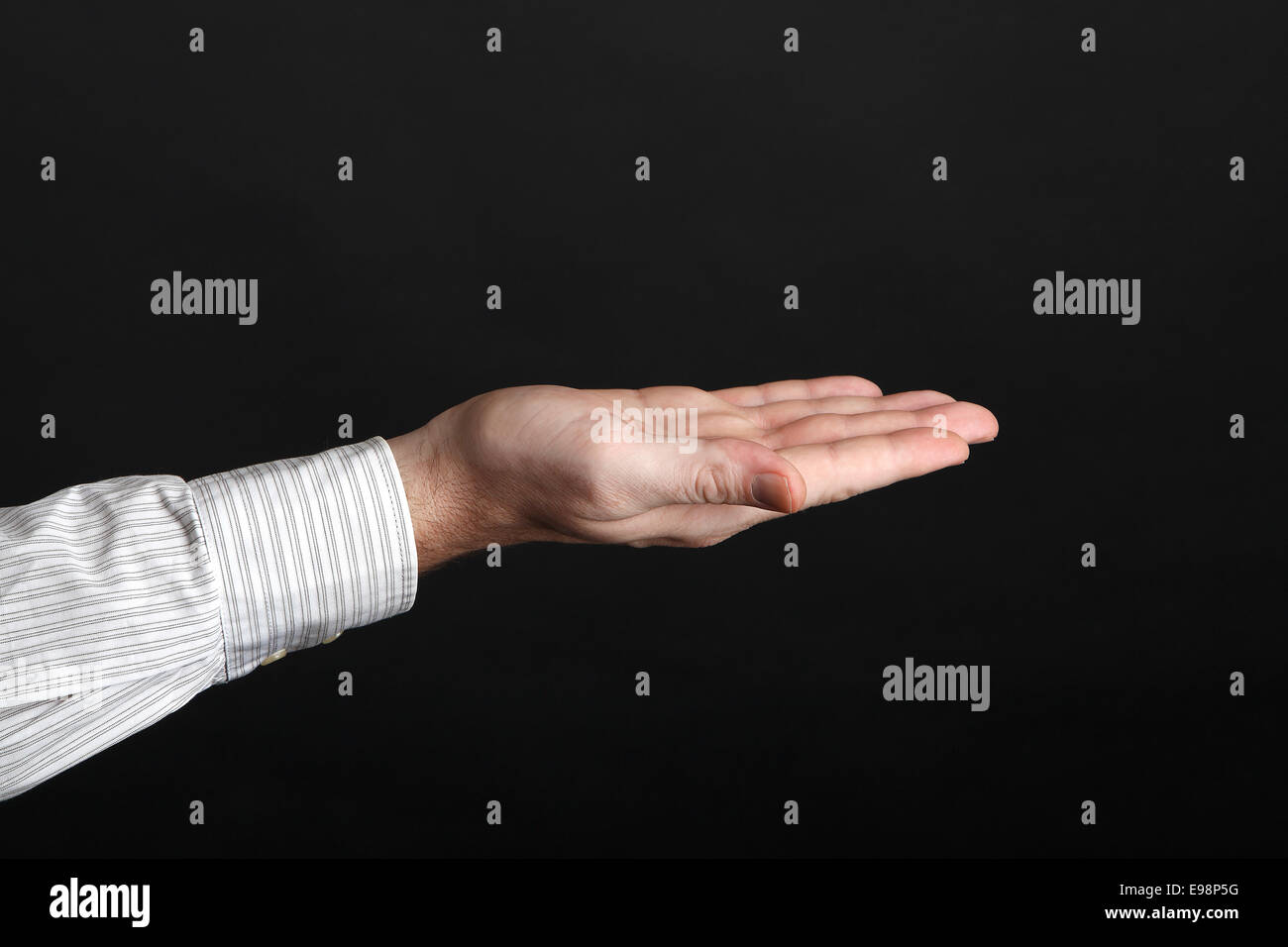 Kaukasische Hand männliche etwas vor schwarzem Hintergrund Stockfoto