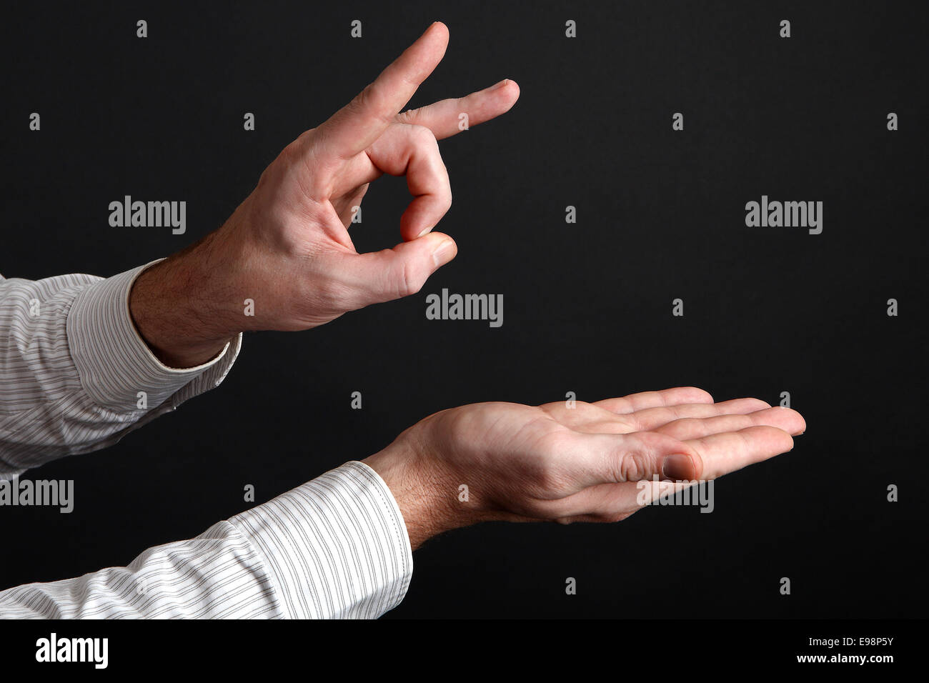 Kaukasische männliche Hände schießen entfernt etwas vor schwarzem Hintergrund Stockfoto