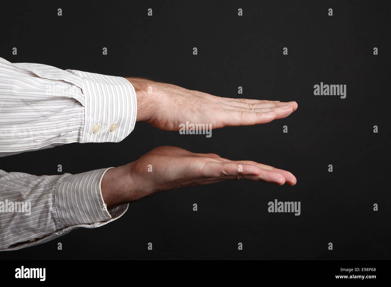 Kaukasische männliche Hände drücken etwas vor schwarzem Hintergrund Stockfoto