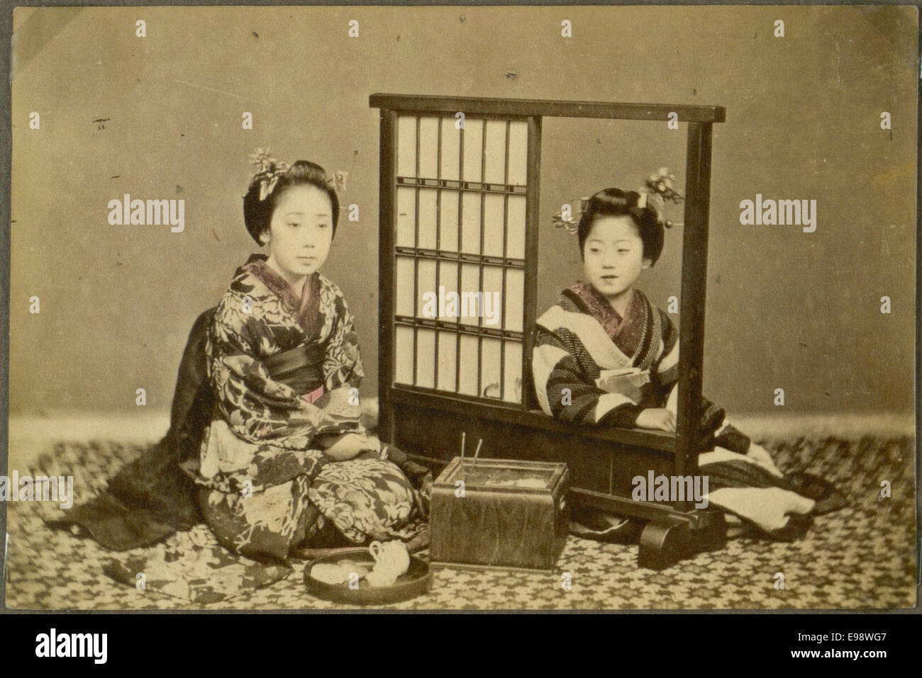 Ein Vintage-Foto, das zwei Frauen in einem traditionellen japanischen Haus zeigt, wahrscheinlich aus den 1930er Jahren Das Bild fängt den Alltag in Japan während des frühen 20. Jahrhunderts ein und zeigt die häusliche Umgebung und kulturelle Traditionen. Stockfoto