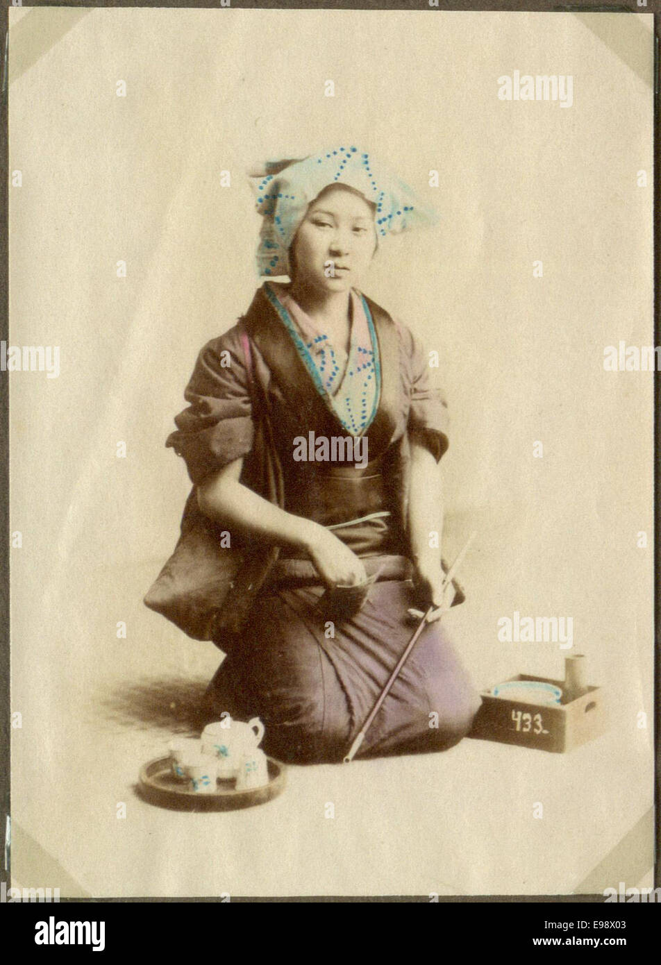 Dieses Bild zeigt eine Frau, die in Japan eine Opiumpfeife raucht und einen Moment des täglichen Lebens aus einer vergangenen Zeit festnimmt. Das Foto spiegelt kulturelle Praktiken und das soziale Leben in Japan während dieser Zeit wider. Stockfoto
