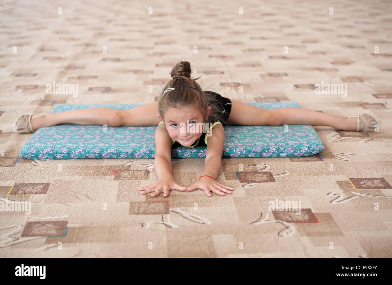 Kleines Mädchen tun Bein-Split auf dem Boden Stockfoto