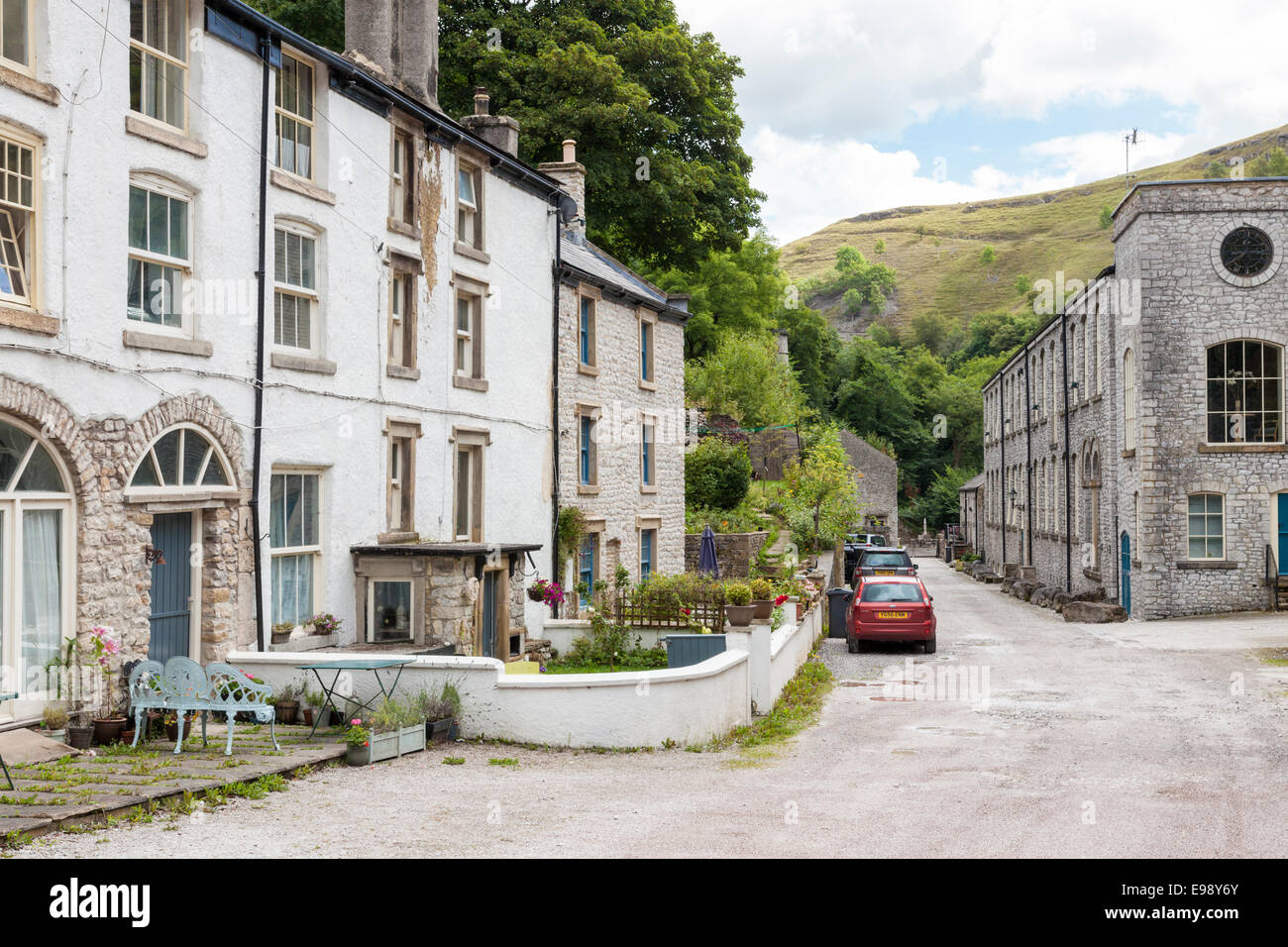 Die Straße und eine Reihe von terrassenförmig angelegten Cottages mit der Mühle (rechts) in der Ortschaft Litton Mill, Derbyshire, England, Großbritannien Stockfoto