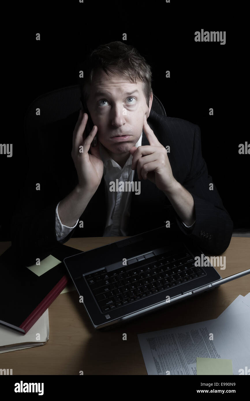 Vertikales Bild der Business-Mann, bereit, sein Temperament während auf seinem Handy zu verlieren Überstunden mit schwarzem Hintergrund Stockfoto