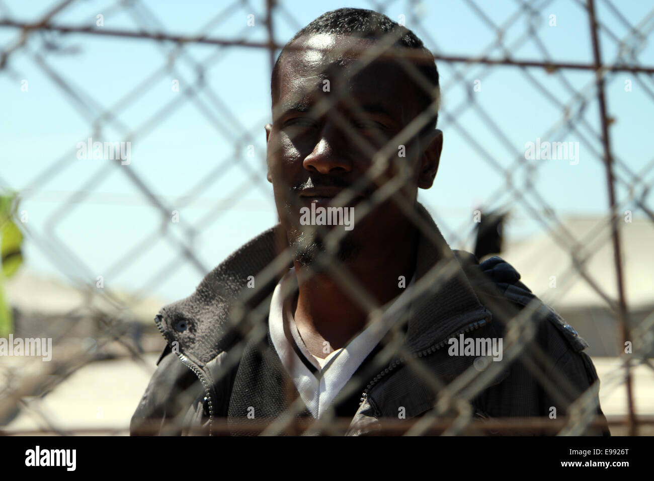 Ein Einwanderer aus Somaliland gesehen durch den Maschendrahtzaun des bei der Hal Far-Zeltstadt in Malta Stockfoto