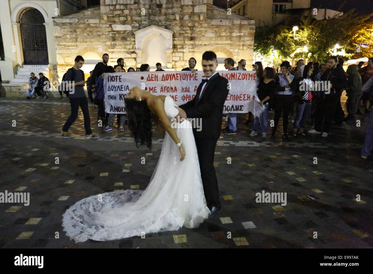 Athen, Griechenland. 22. Oktober 2014. Ein Brautpaar darstellen für ihre Hochzeitsfotos auf dem Monastiraki Platz, während im Hintergrund der Protestmarsch vergeht. Shop-ArbeiterInnen und Besitzer vereint in einem Protest gegen die Eröffnung der Geschäfte in Griechenland am Sonntag. Das Gesetz, das Geschäfte an Sonntagen öffnen zu können wurde in diesem Sommer und soll die Umsatzsteigerung von Geschäften und 300.000 neue Arbeitsplätze zu schaffen. Bildnachweis: Michael Debets/Alamy Live-Nachrichten Stockfoto Athen, Griechenland. 22. Oktober 2014. Ein Brautpaar darstellen für ihre Hochzeitsfotos auf dem Monastiraki Platz, während im Hintergrund der Protestmarsch vergeht. Shop-ArbeiterInnen und Besitzer vereint in einem Protest gegen die Eröffnung der Geschäfte in Griechenland am Sonntag. Das Gesetz, das Geschäfte an Sonntagen öffnen zu können wurde in diesem Sommer und soll die Umsatzsteigerung von Geschäften und 300.000 neue Arbeitsplätze zu schaffen. Bildnachweis: Michael Debets/Alamy Live-Nachrichten Stockfoto