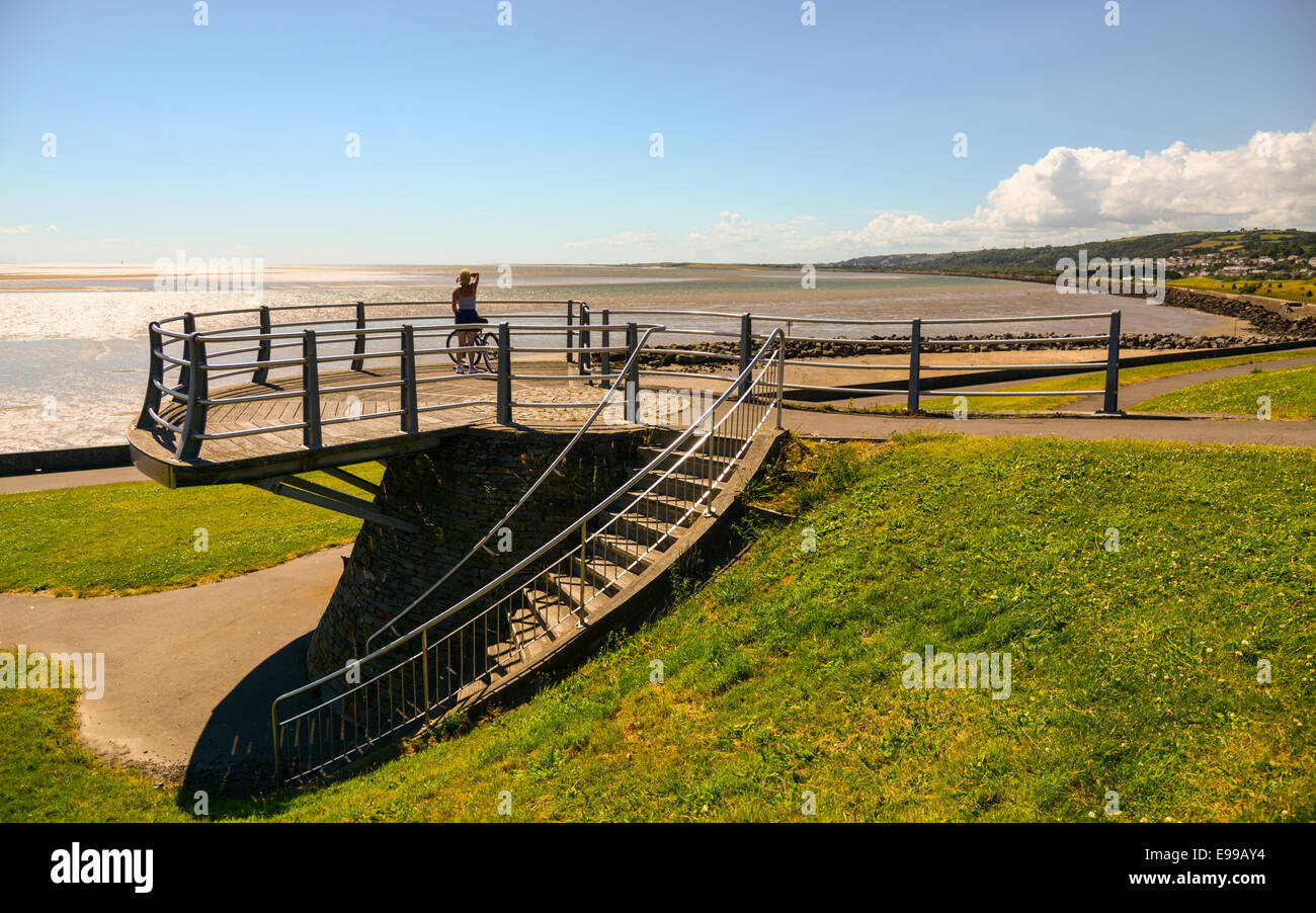 Ein Frau Radfahrer blickt in Richtung Burry Port von einer Aussichtsplattform auf dem Millennium Küstenpfad, Wales. Stockfoto