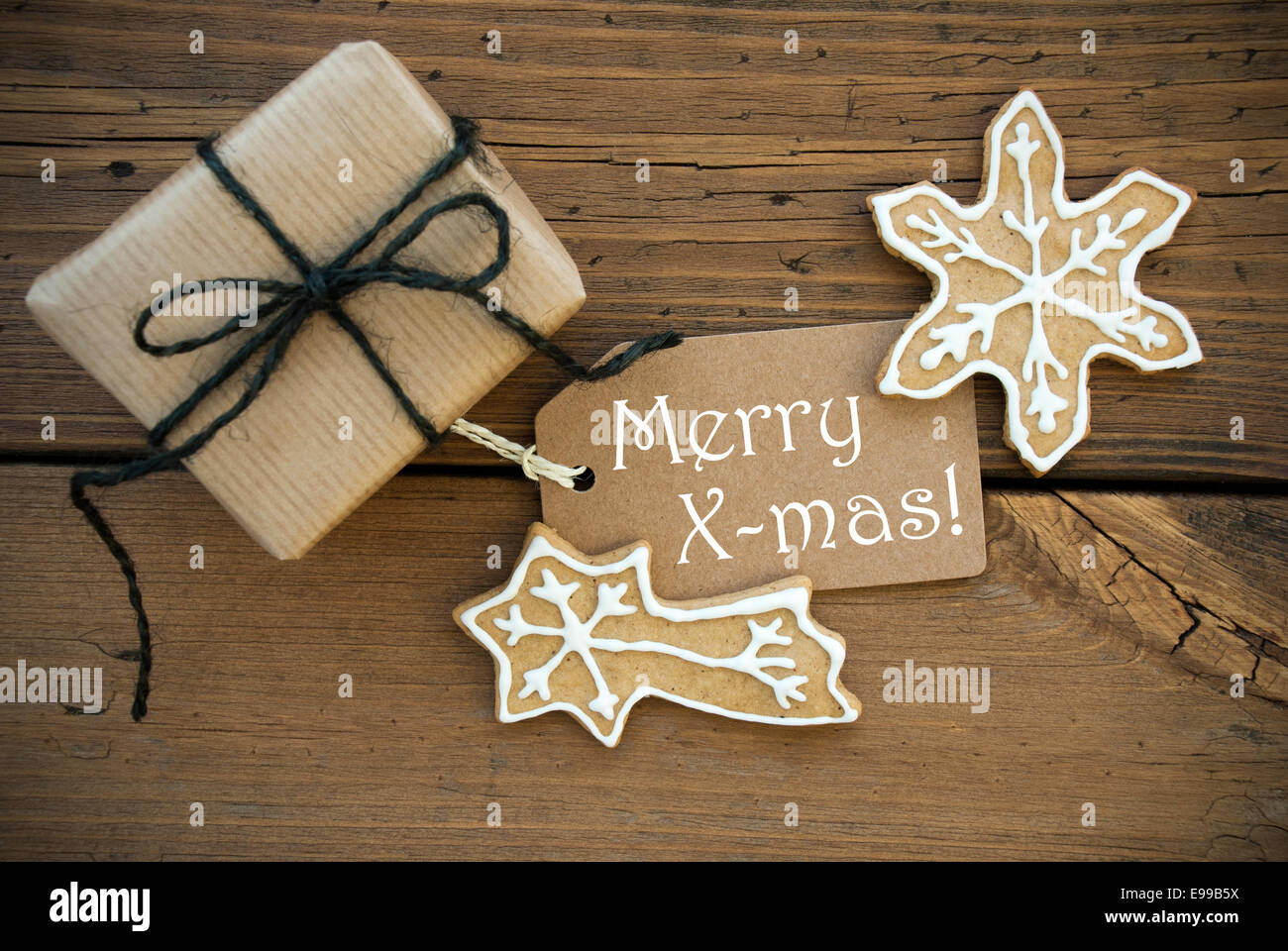 Eine weiße Frohe Weihnachten auf einem braunen Etikett mit Weihnachtsdekoration auf Holz Stockfoto