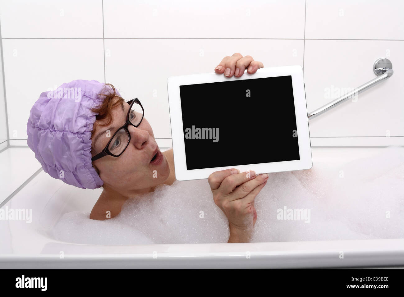 Begeisterte Frau in der Badewanne mit Tablet-PCs, Nahaufnahme Stockfoto