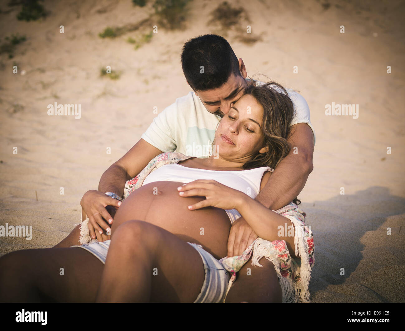 Glücklich schwanger paar am Strand im Freien. Paar ist in den Sand. Stockfoto