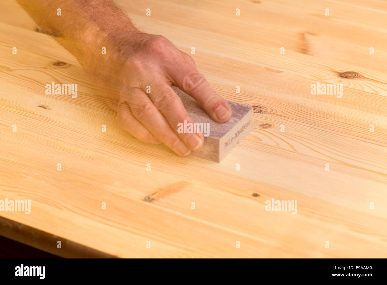 Mans Hand auf Schleifblock auf Kiefernholz Stockfoto