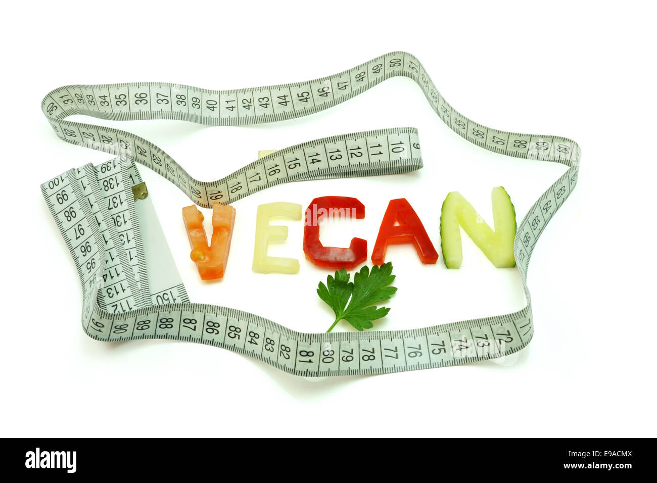 Wort Vegan bestehend aus Scheiben von verschiedenen Gemüsen mit Maßband auf weißem Hintergrund. Vegane Ernährung Stockfoto