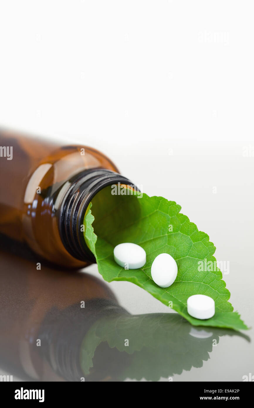 Blatt und Pillen in einer kleinen Flasche Stockfoto