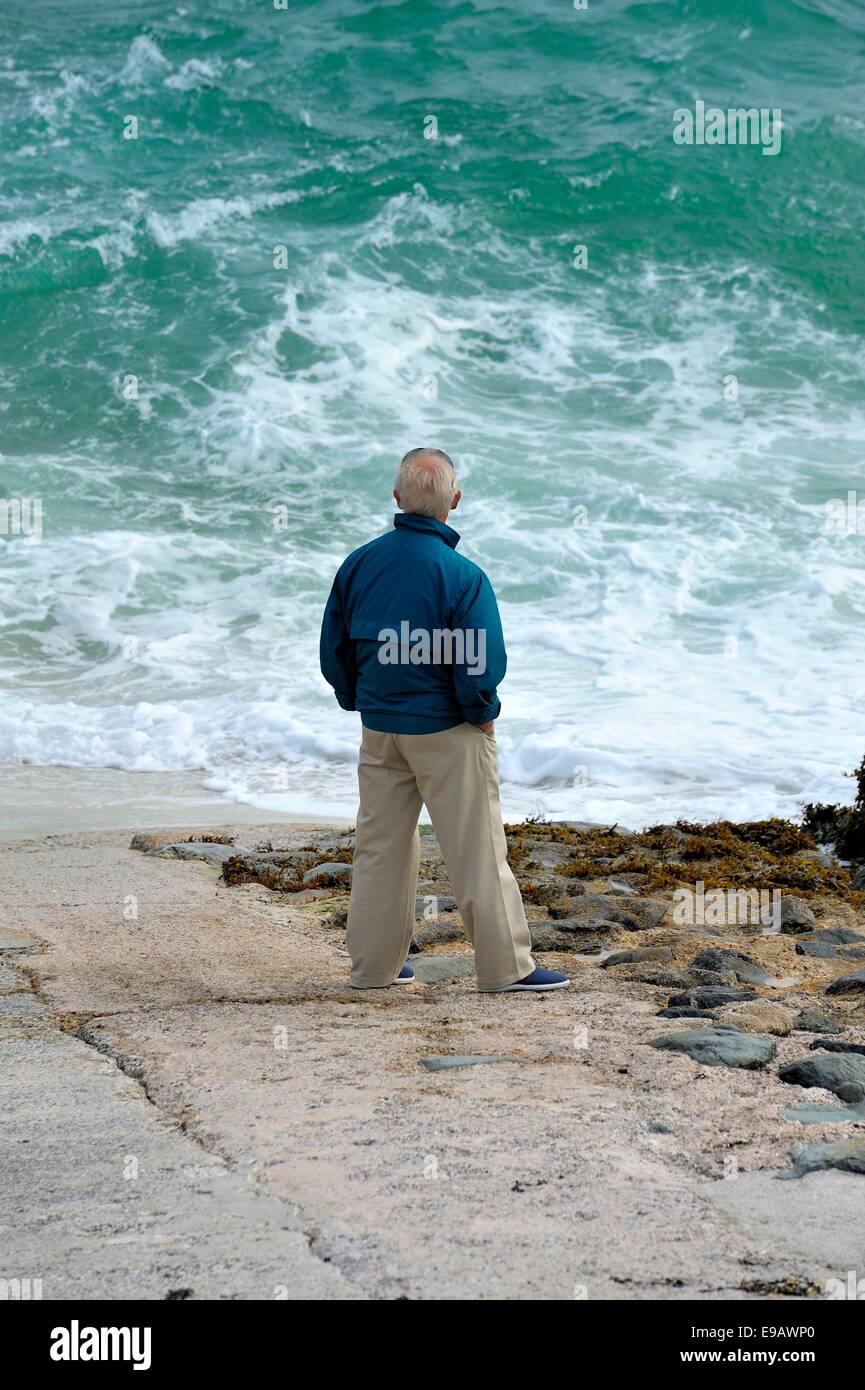 Ein senior woman Blick auf eine aufgewühlte Meer St Ives Cornwall England uk Stockfoto