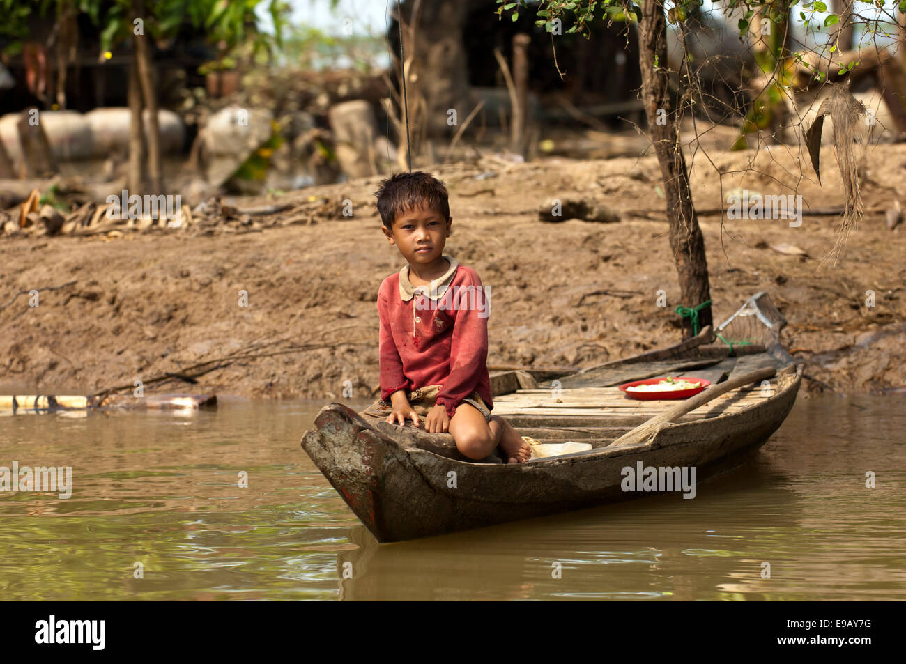 Junge sitzt in einem traditionellen Boot am Fluss Sangker in Battambang, Provinz Battambang, Kambodscha Stockfoto
