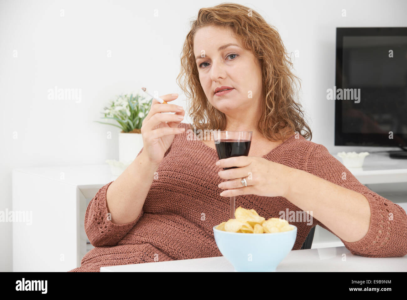 Frau rauchen Zigaretten und trinken Wein und Essen Snacks Stockfoto