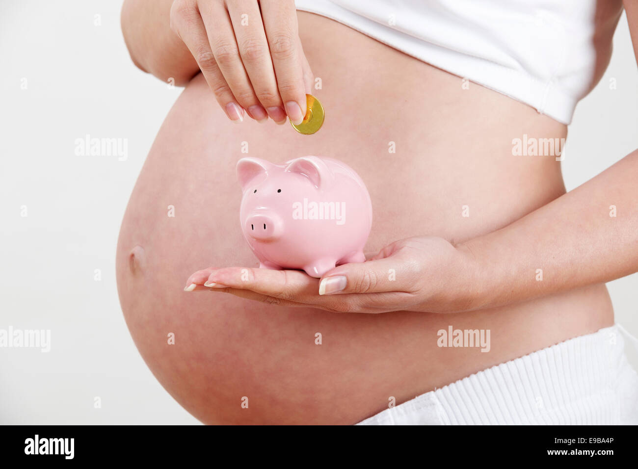 Nahaufnahme von Schwangeren, Münze ins Sparschwein Stockfoto