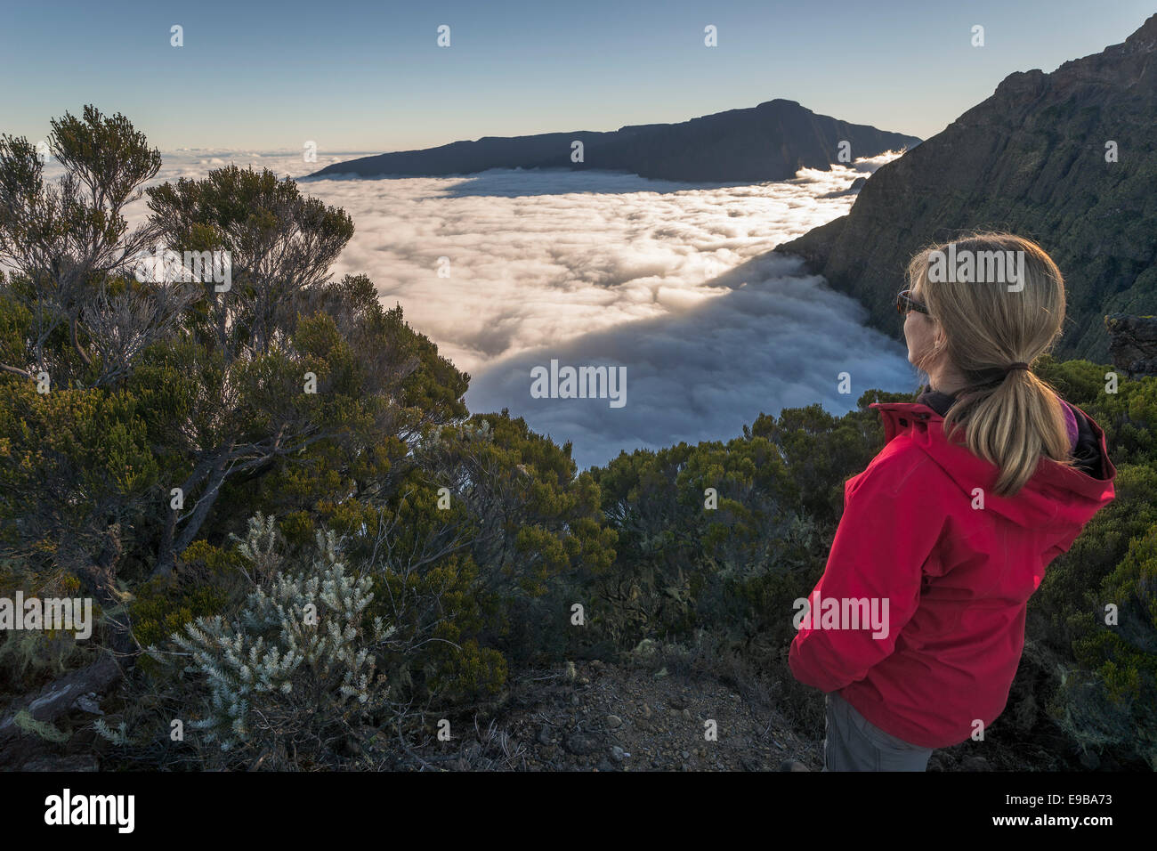 Junge Frau mit Blick auf ein Meer von Wolken über Cilaos Becken, Cirque de Cilaos, Reunion, Afrika Stockfoto