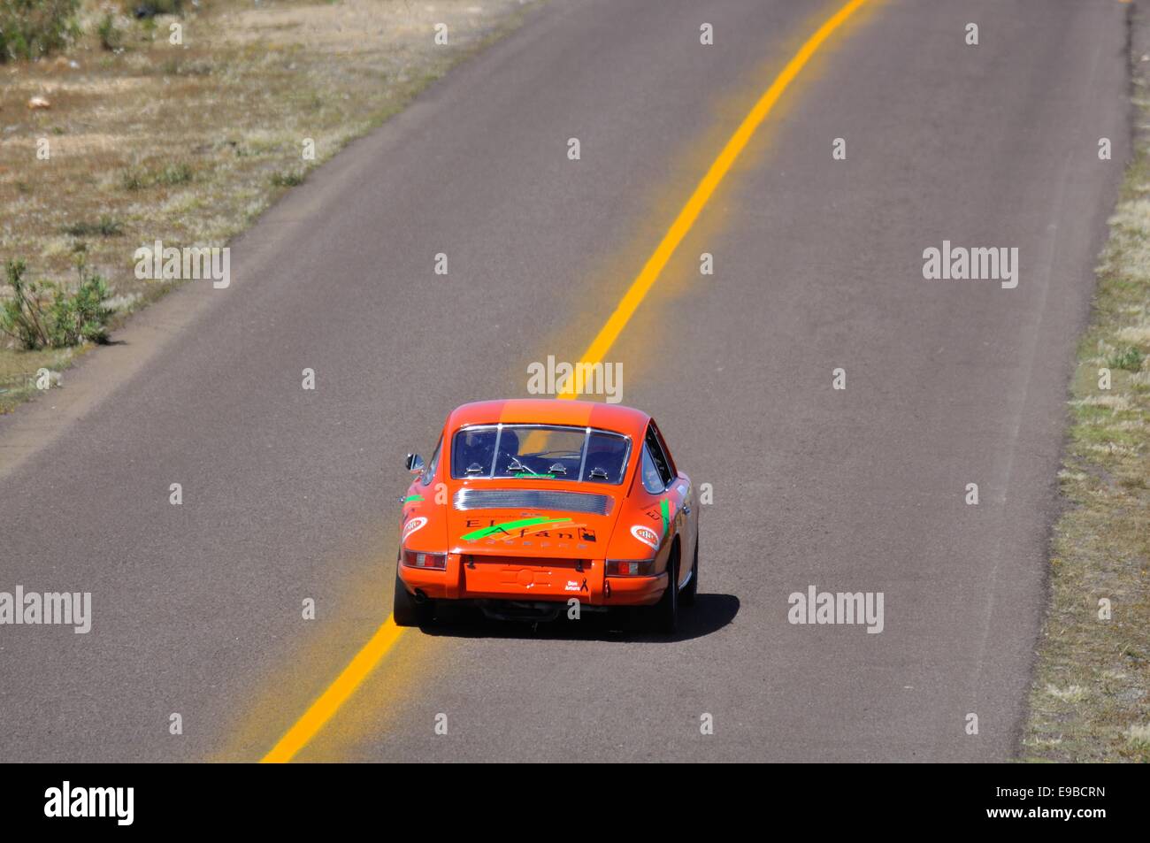 Rückansicht des eine orange Porsche 911 Rennwagen Beschleunigung entlang einer Autobahn im Straßenrennen Carrera Panamericana in Mexiko Stockfoto