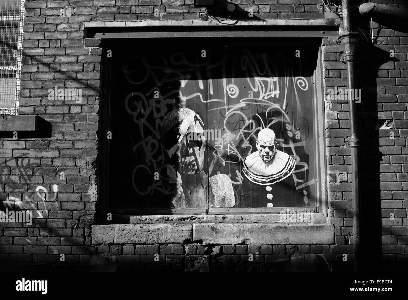 Ein Graffiti-Bild von einem unheimlich aussehende Clown auf die hölzerne Laderampe Tür einer heruntergekommenen Fabrik gemalt Stockfoto