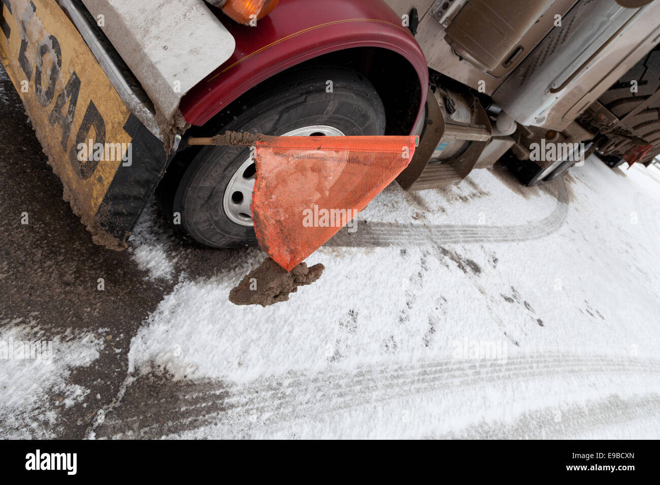 Peterbilt 379 Auflieger mit einem flatdeck übergroße Belastung von großen Riesen großen Mining Reifen mit Warnung flags Schnee und Eis im Faltblatt Winter abgedeckt Stockfoto