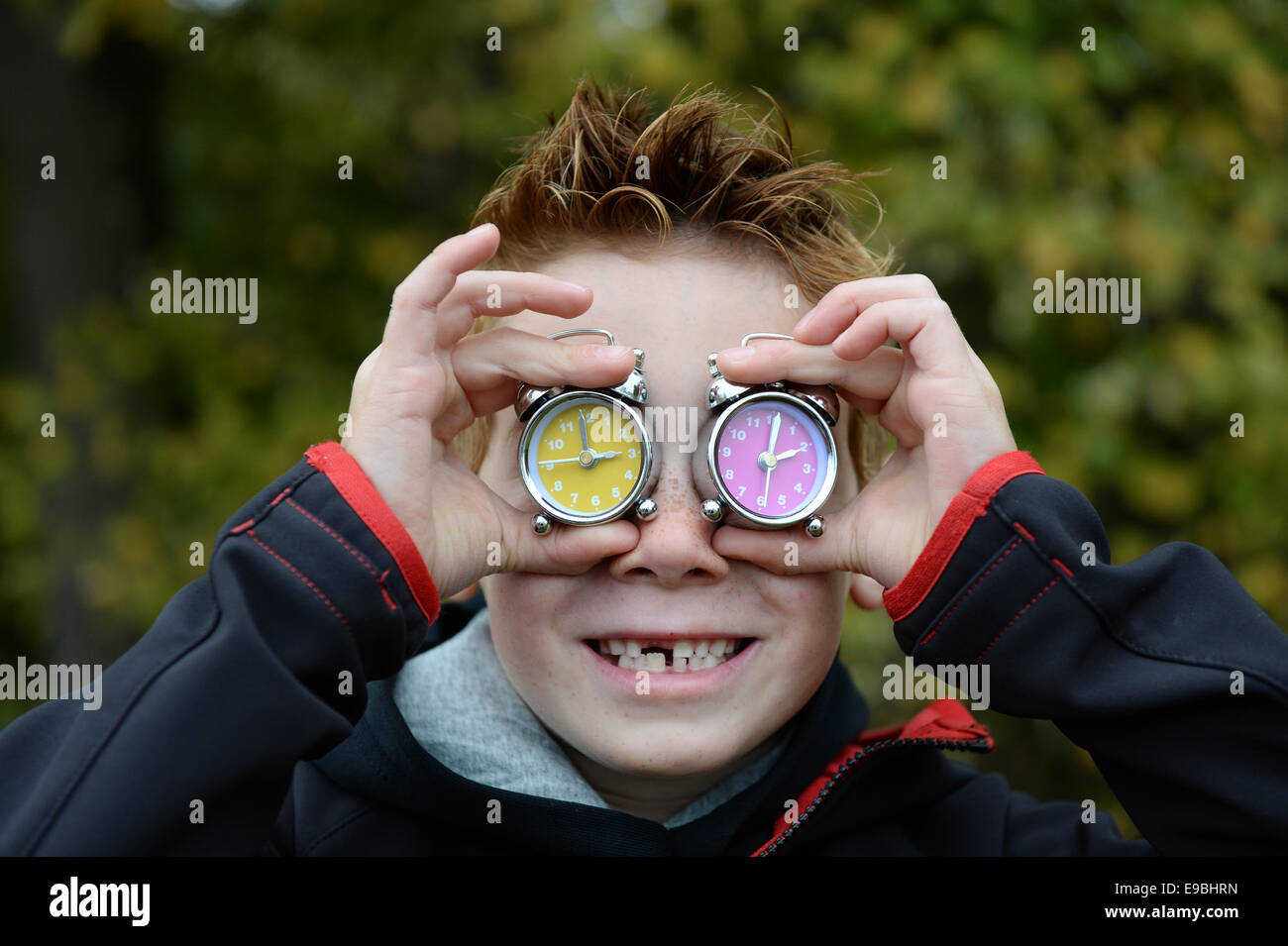 Friedrichshafen, Deutschland. 23. Oktober 2014. Grundschule Schüler Vincent hält zwei Wecker vor seinem Gesicht in Friedrichshafen, Deutschland, 23. Oktober 2014. Uhren werden auf Winterzeit am 26. Oktober 2014 um eine Stunde zurückgedreht werden. Foto: Felix Kaestle/Dpa/Alamy Live News Stockfoto